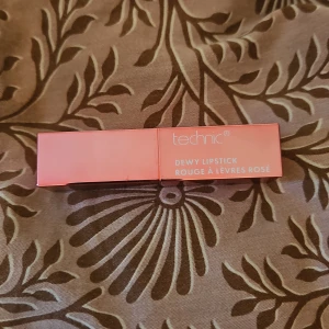 Rosa läppstift från Technic - Säljer ett rosa dewy läppstift från Technic. Förpackningen är stilren och kompakt, perfekt för att ha med i väskan. Läppstiftet ger en glansig finish och är lätt att applicera.