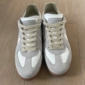 Maison Margiela sneakers, strl 43 - Snygga sneakers från Maison Margiela, passar utmärkt nu till sommaren. Skorna är endast använda ett fåtal gånger, skick 9/10! Endast dustbag medföljer. Hör av er vid frågor eller om fler bilder önskas :)).                                     Självklart kan priset diskuteras i rimliga vägnar:)