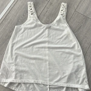Vit linnetopp från H&M - Säljer en vit linnetopp från H&M med flätade axelband. Perfekt för varma sommardagar. Toppen har en enkel och stilren design som passar till det mesta. Skön och luftig att bära.