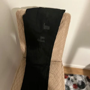 Svarta jeans med slitningar - Snygga svarta jeans med coola slitningar på framsidan. De har en klassisk femficksdesign och knäppning i midjan. Perfekta för en avslappnad stil.