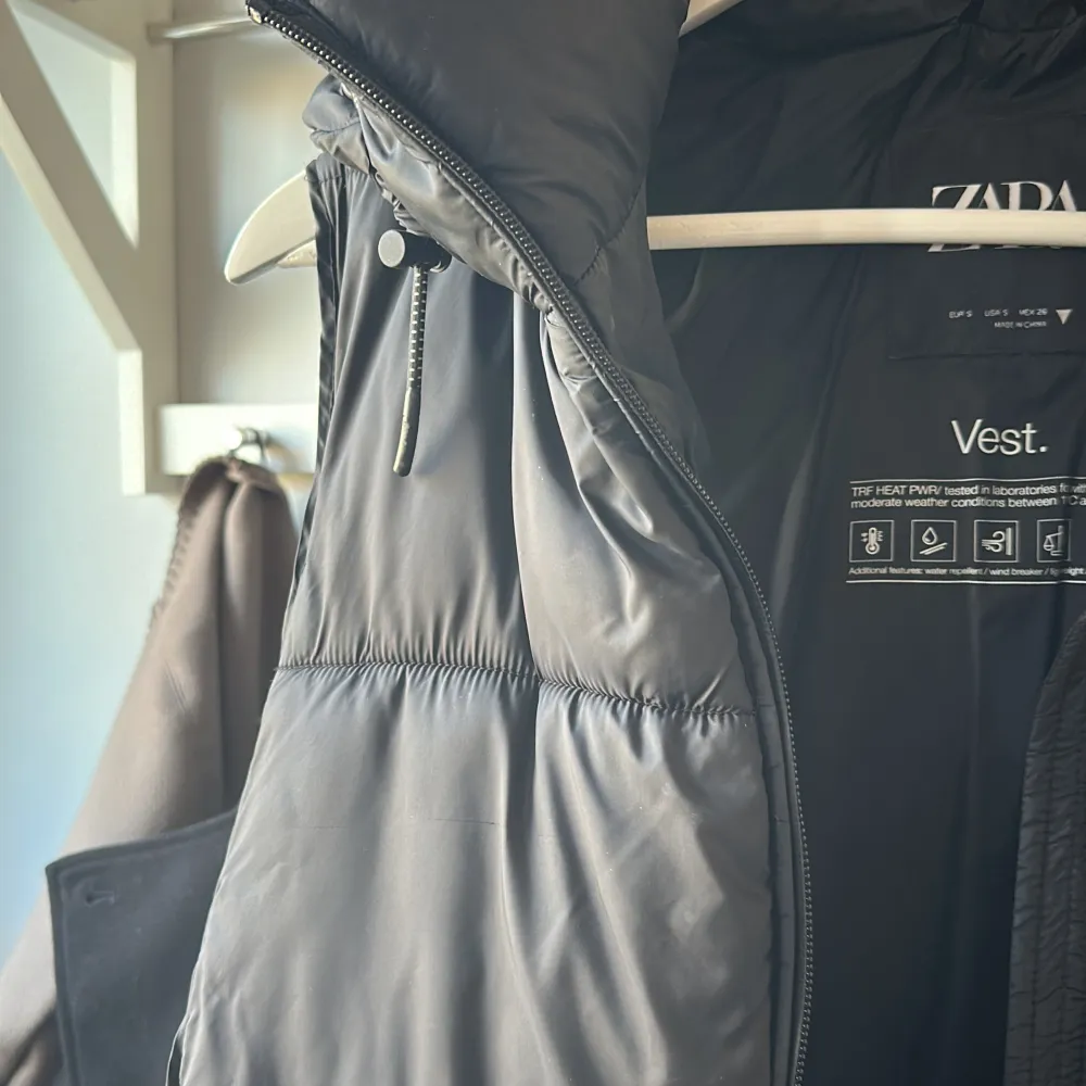 Snygg svart dunväst från Zara med dragkedja och hög krage. Perfekt för lager-på-lager under kyliga dagar. Västen har en stilren design och är lätt att matcha med olika outfits. Använd fåtal gånger så är i väldigt fint skick🥰. Takit.