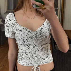 Vit prickig topp  - Säljer en söt vit topp med svarta prickar och snörning framtill. Supersnygg nu till sommaren men lite för stor för mig💕💕 Den är märkt M men passar absolut S skulle jag säga💕På sista bilden ser ni baksidan som är stretch💕 