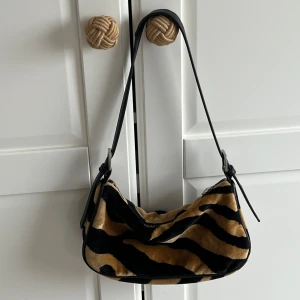 Zebramönstrad axelväska med dragkedja - Snygg axelväska med zebramönster i svart och beige. 