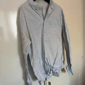 Peak Performance - Säljer en stilren ljusblå skjorta från Peak Performance. Skjortan har en klassisk krage och knappar framtill. Perfekt för en avslappnad men ändå uppklädd look.