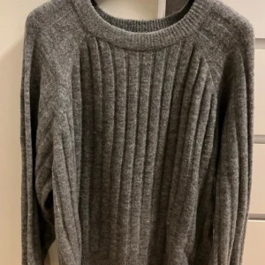 Grå ribbad tröja från Lager 157 - Säljer en stilren grå ribbad tröja från Lager157. Tröjan har en rund hals och långa ärmar, perfekt för kyligare dagar. Den är tillverkad i ett mjukt material som ger en skön känsla. Passar utmärkt till både jeans och kjol. 🩶