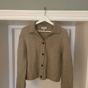 Beige kofta från & Other Stories - Säljer en beige kofta från & Other Stories. Koftan har långa ärmar och knappar framtill. Storlek M. Den är tillverkad i en mjuk blandning av alpacka, polyamid och ull. Den är använd och därav nopprig på insidan av armarna (se bild). 