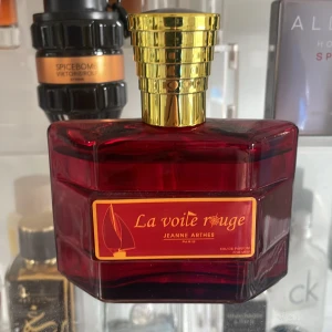 La Voile Rouge Eau de Parfum från Jeanne Arthes - Elegant parfym i en djup röd flaska med guldlock. La Voile Rouge från Jeanne Arthes är en doft som utstrålar lyx och stil. Perfekt för den som vill ha en sofistikerad och unik doftupplevelse. Använt 20 sprays ungefär 🤩😀🤩