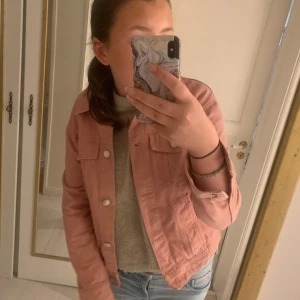 Rosa jeansjacka - Säljer en snygg rosa jeansjacka med knappar framtill och två bröstfickor. Jackan har en klassisk krage och långa ärmar. Inga större defteker. Perfekt för vår och sommar! Säljer då den är för liten.  Skriv för fler bilder eller annat! 💗