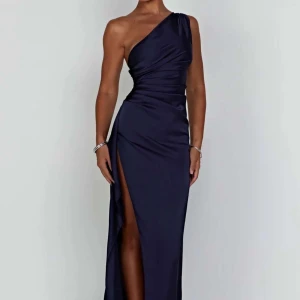 Mörkblå one-shoulder klänning/balklänning - Elegant mörkblå långklänning/balklänning med one-shoulder design och hög slits. Perfekt för en glamorös kväll eller bal 💙säljer åt en kompis då den ej passade, var perfekt längd för 160 och skulle säga lite liten i storleken men passar fortfarande om du har S i vanliga fall, aldrig använd! Endast testad 