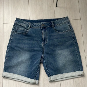 Blå jeansshorts från Stories - Snygga blå jeansshorts från Stories i storlek 40. De har en klassisk femficksdesign och uppvikta benslut för en avslappnad look. Perfekta för sommardagar!