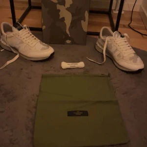 Valentino Rockrunner i vit och grå kamouflage - Snygga Valentino Rockrunner sneakers i en stilren vit och grå kamouflagedesign. Skorna har en robust sula och klassisk snörning. Perfekta för att ge din outfit en exklusiv touch.
