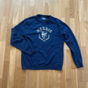 Blå tröja från Morris - Säljer en snygg blå tröja från Morris med ett tryck på bröstet. Tröjan har långa ärmar och en rund halsringning. Perfekt för en stilren look.