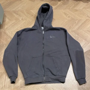 Grå hoodie från Karl Kani - Säljer en stilren grå hoodie från Karl Kani med dragkedja och broderad logga på bröstet. Väldigt loose fit storlek S men sitter mer som M. Knappt använd inköpt för 800kr