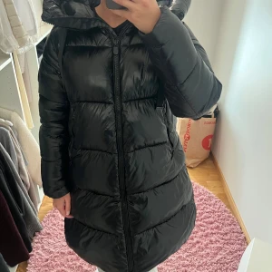 Lång pufferjacka från save the duck - Superfin pufferjacka från save the duck. Jackan är glansig i materialet och är en lång modell. Fri från defekter och skötsamt använd. Jag är 160 cm och har strl S🩷