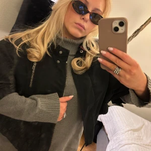 Svart bomberjacka från DKNY Jeans - Snygg svart bomberjacka från DKNY Jeans med dragkedja och knappar. Jackan har en cool, loose passform och är perfekt för höst och vår. Den har praktiska fickor och en justerbar nederkant med snörning. Perfekt för en stilren look!