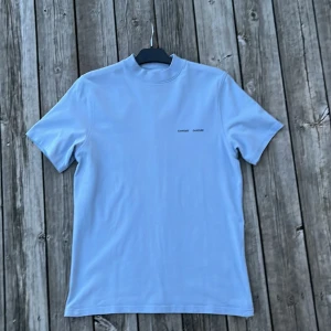 Ljusblå t-shirt från Samsøe  - Snygg ljusblå t-shirt från Samsøe  med korta ärmar och en minimalistisk design. Perfekt för streetwear stilen. Riktigt snygg på sommaren med lite bränna. Passar även bra som pumpcover till gymmet. Storlek S. Hör av dig vid funderingar.