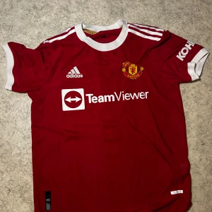 Röd Manchester United fotbollströja - Säljer en röd Cristiano Ronaldo, Manchester United fotbollströja (2021 säsongen om jag inte minns fel). Använd 1-2 gånger, i nyskick. Köpt från unisport i Köpenhamn för ca 1200, mitt pris 600