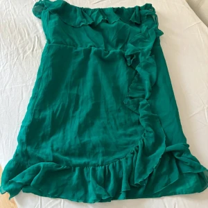 Grön klänning från H&M - Säljer en vacker grön klänning från H&M med volangdetaljer. Klänningen är axelbandslös och har en luftig passform Storlek L men passar även storlek M #summerdress
