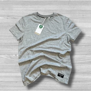 Björn Borg t-shirt - Säljer en stilren grå t-shirt från Björn Borg. Den har en normal passform och är tillverkad i mjuk bomull. Perfekt för en avslappnad look. T-shirten har en diskret etikett nertill och en randig detalj vid kragen.