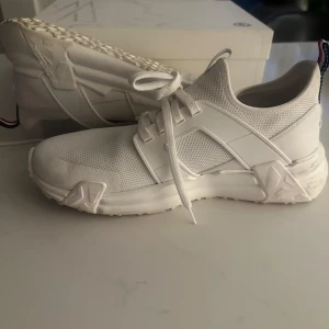Vita sneakers från Moncler - Snygga vita sneakers från Moncler med en stilren design. Skorna har snörning och en bekväm passform. Perfekta för en trendig look.