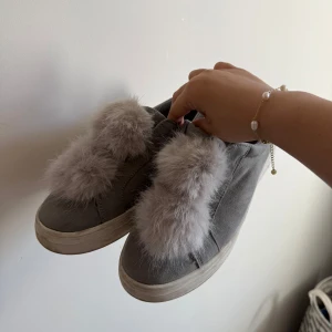 Duffy skor  - Snygga grå sneakers med fluffiga pälsdetaljer på ovansidan. Perfekta för att ge en unik touch till din outfit. Skorna har en rund tå och en bekväm sula.
