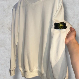 Vit Stone Island Sweatshirt - Vit Stone Island Sweatshirt, Storlek L, Mycket bra skick. Liten liten defekt syns på sista bilden men bedömer ändå skicket som mycket bra. Köp den nu via köp nu funktionen innan någon annan hinner före💸  Postar alltid inom 24h📦  Tveka inte att höra av dig om du har frågor🧐  Lägg ett prisförslag om du tycker det är för dyrt💸  Kolla min profil för andra fina kläder🛍️