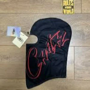 svart och röd corteiz balaklava  - Snygg svart balaclava med coolt rött graffiti-tryck. Perfekt för att hålla sig varm och stilren under kyliga dagar. Tillverkad i ett mjukt och bekvämt material. helt ny