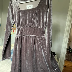 Unik grå klänning  - Fin grå klänning i lent tyg. Går att dra åt i midjan och knytas bak. Aldrig använd.
