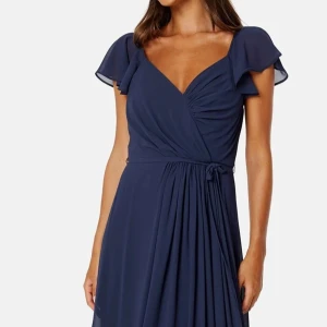 Balklänning  - Elegant marinblå långklänning med v-ringning och volangärmar. Klänningen har en omlott-design och ett knytband i midjan för en smickrande passform. Perfekt för balen! Storlek 36 och använd 1 gång. Nyskick! Helt slutsåld på hemsidan. 