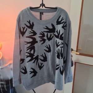 Grå stickad tröja med fågelmönster från Rainbow - Säljer en grå stickad tröja från Rainbow med ett coolt svart fågelmönster. Tröjan har långa ärmar och en rund halsringning. Perfekt för en avslappnad stil. Hör av dig vid intresse!
