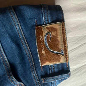 Blå jeans från Jacob Cohen - Snygga blå jeans från Jacob Cohen med knappgylf och klassisk femficksdesign. Jeansen är i nyskick.