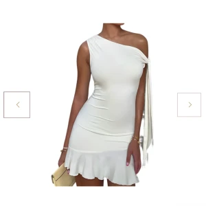 Vit one-shoulder klänning - Vit one-shoulder klänning från Dressy.se med volangdetalj vid fållen. Klänningen har en knytning vid axeln som också går att ta av om man föredrar utan. Köpt för 349kr. Aldrig använd då den var för stor. Storlek S.