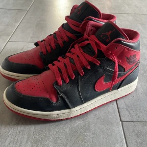 Svarta och röda Nike Air Jordans - ⚠️SKORNA TVÄTTAR MED SKO PUTS INNAN SÄLJNING⚠️. Säljer ett par klassiska Nike Air Jordans i svart och rött. Skorna har en ikonisk design med snörning och rund tå. Perfekta för dig som vill ha en stilren och sportig look.