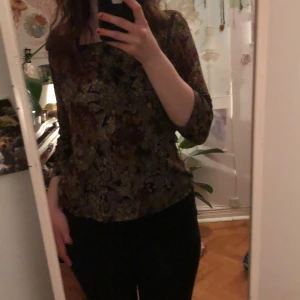 Blommig långärmad topp - Säljer en blommig topp med lång ärm i jordnära färger. Perfekt för höst och vår med sitt unika mönster och bekväma passform. Passar bra till både jeans och kjol.