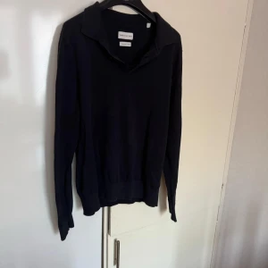 These Glory Days - Säljer en stilren mörkblå tröja från These Glory Days i superior bomull. Tröjan har en klassisk krage och långa ärmar, perfekt för en avslappnad men ändå snygg look. Passar bra till både jeans och chinos.