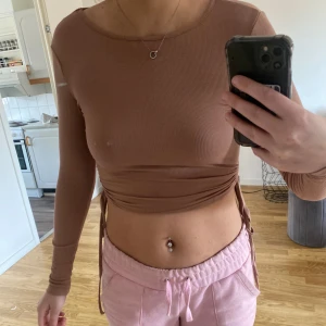Beige ribbad croppad topp - Säljer en beige ribbad croppad topp med långa ärmar och knytning i sidan. Perfekt för en trendig look.