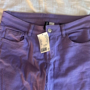Jeans  - Säljer ett par lila jeansbyxo. Byxorna har klassisk ficksdesign, stängs med dragkedja och knapp. Perfekta för dig som vill sticka ut med färg i vardagen.
