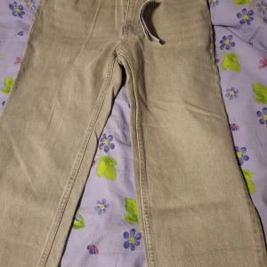 Grå jeansbyxor med raka ben - Säljer ett par klassiska grå jeansbyxor med raka ben och normal passform. Byxorna har fem fickor, knapp och dragkedja i gylfen samt bälteshällor. Perfekta för en stilren och enkel look.