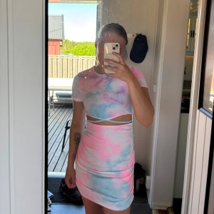 Pastellfärgad kortklänning med cut out-detalj - Säljer en tight kortklänning i pastellfärger med rosa, blått och vitt. Klänningen har korta ärmar, rund hals och en snygg cut out-detalj vid midjan. Perfekt för sommarens alla tillfällen!