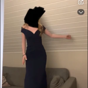 Marinblå balklänning från bubbleroom - Elegant marinblå långklänning från Goddiva London (bubbleroom) med offshoulder-skärning och figurnära passform. Klänningen har en djup v-ringning och är perfekt för bal eller fest. Tidlös och stilren design som framhäver siluetten. Skickar direkt