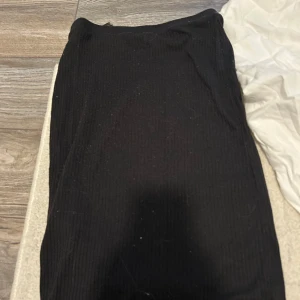 Svart ribbad kjol från H&M - En svart ribbad kjol från H&M med enkel och stilren design. Kjolen är stretchig och har en rak passform som passar till många olika looks. Perfekt för dig som gillar minimalistisk stil.