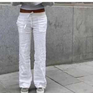 Alobha linnebyxor - Säljer ett par vita linnebyxor med normal passform och knytband i midjan. Byxorna har raka ben och är perfekta för en avslappnad stil. Supersköna och luftiga, passar perfekt till sommaren.