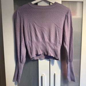 Ljuslila stickad croppad tröja - Säljer en ljuslila stickad tröja med croppad passform och långärmade ärmar. Tröjan har ett diskret mönster och bredare ribbad kant nedtill samt vid ärmsluten. Skriv privat för fler bilder 🩷