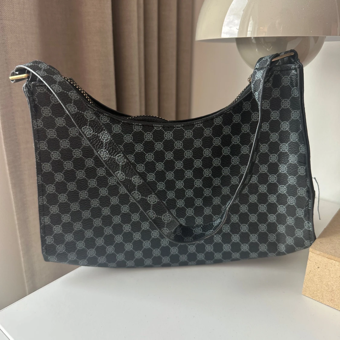 Svart axelväska med monogrammönster 