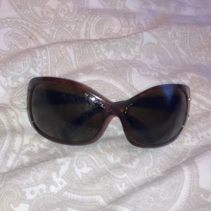 Bruna oversized solglasögon från Prada - Snygga oversized solglasögon från Prada i brun plast med mörka glas. Bågarna har en lätt glansig finish och diskret Prada-logga sidorna