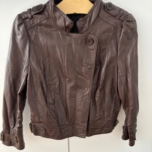 Skinnjacka - Röd/brun Skinnjacka med tre kvartsärmar, något kortare midja. Knappt använd men hängt i garderoben ett tag.