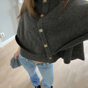 Mörkgrå stickad kofta med knappar - En poncho från zara i en mörkgrå färg. Inte använt så mycket ❤️