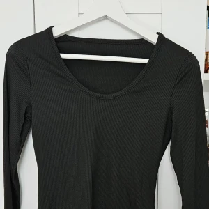 Svart ribbad långärmad topp - Säljer en svart långärmad topp med rund halsringning och ribbad struktur. Perfekt basplagg som är enkel att matcha till olika outfits. Snygg och stilren modell som passar året runt.