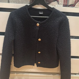 Svart kofta från gina Tricot med guld knappar  - Jätte fin och bekväm tröja, väldigt härlig för sommaren och hösten. Storleken är xs men kan även användas om man har s. Valde att sälja koftan på grund av att det inte är min still och ville helst inte slänga den. Har inte används för och är i nyskick