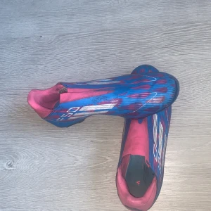 Blå och rosa fotbollsskor Adidas F50’s - Säljer ett par Adidas F50’s Academy. Inga snören vilket underlättar situationen med aty knyta och knyta av.  Inga skador på skon någonstans utan de har varit använda ett par gånger. Perfekt för dig som vill sticka ut på plan!